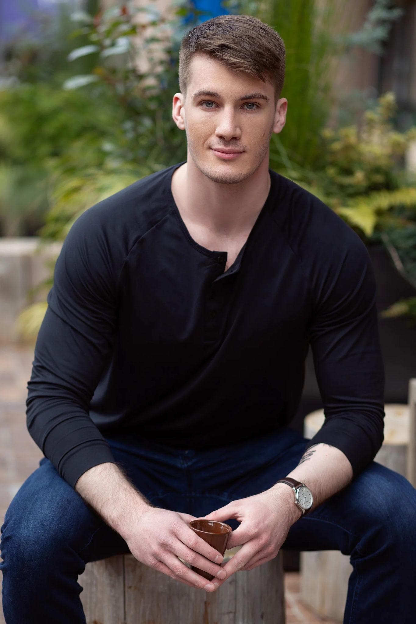 Man in a black henley sitting for a posed outdoor portrait